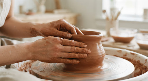 Manos trabajando con arcilla terracota en un torno de alfarero